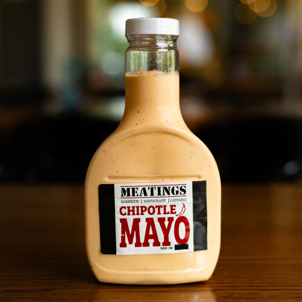 Bottle of MEATINGS Chipotle Mayo on a wooden surface with a blurred background