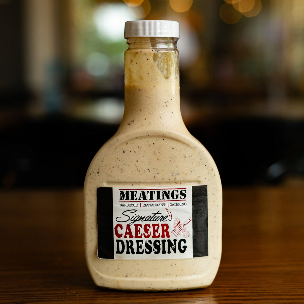 Bottle of Meatings Caesar dressing on a wooden surface with a blurred background
