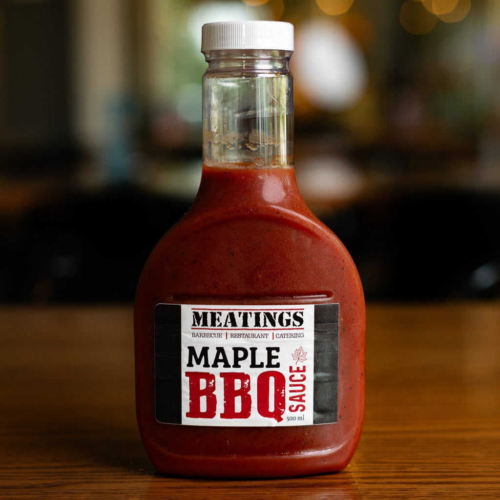 Bottle of MEATINGS Maple BBQ Sauce on a wooden surface with blurred background
